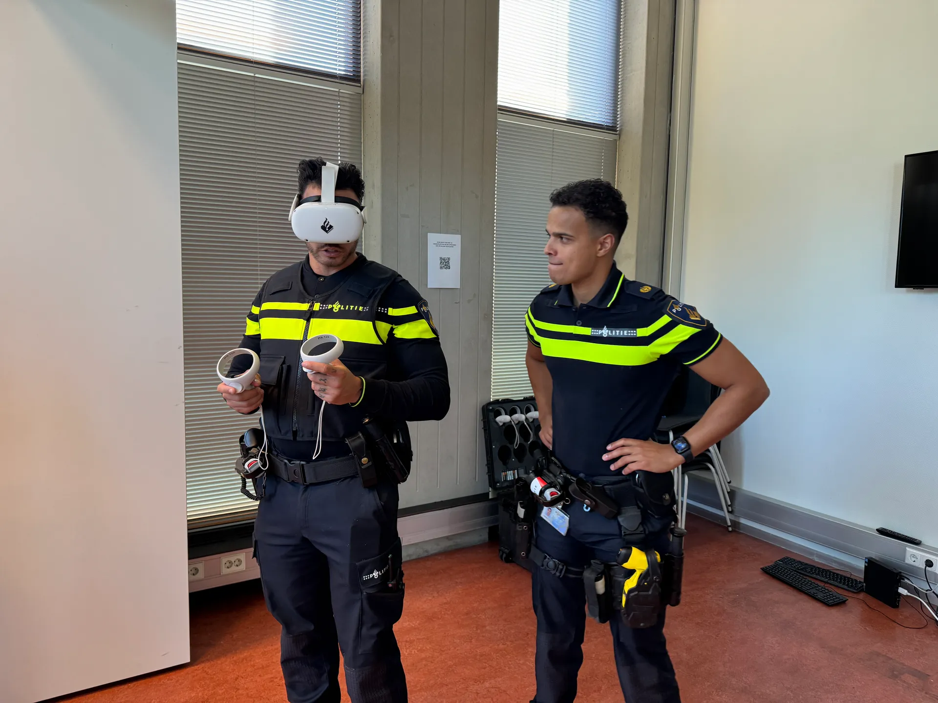 Two police officers testing the training, one wearing a VR headset.